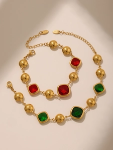 Detailed view of 18K gold plated stainless steel jewelry set with red and green gems