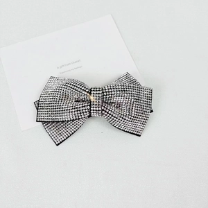 Close-up of elegant bow hair clip with sparkling silver rhinestones on black metal base
