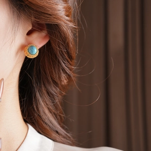 Close-up of 18k gold plated earring with turquoise dome stone worn by a model