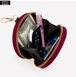 Deep burgundy round leather coin purse with golden zipper showing interior storage capacity