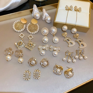 Set di orecchini dorati con perle e strass caratterizzato da fiocchi e disegni geometrici