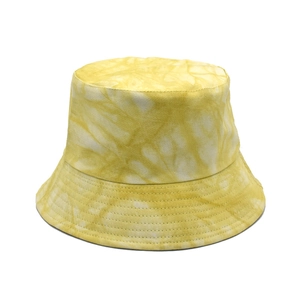 Détail d'un chapeau bob tie-dye jaune et blanc avec coutures renforcées sur le bord
