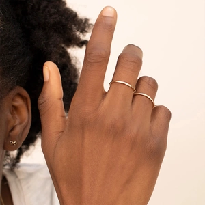 Detail shot of elegant gold minimalist stackable rings and infinity symbol stud earrings