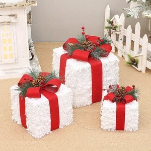 Close-up of white flocked Christmas gift boxes with red bows and pine cone details