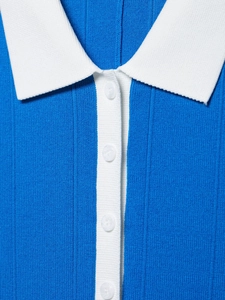 Dettaglio dell'abito in maglia blu con colletto a polo bianco e bottoni in primo piano