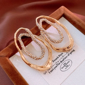 Macro detail of gold-plated double-layer oval earrings with sparkling cubic zirconia