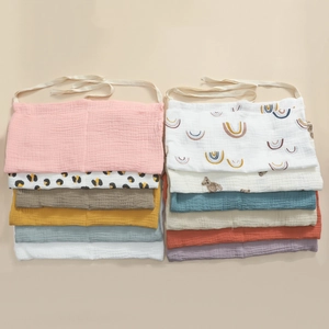 Detailed view of folded cotton gauze baby bibs in various patterns and soft colors