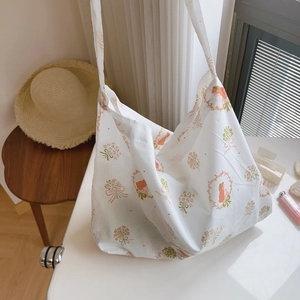 Detail of floral and bow prints on a white cotton tote bag in a casual lifestyle setting