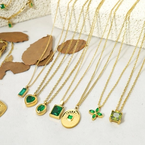 Detailed view of various green gemstone pendants in gold plating on stone background