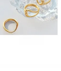 Macro view of gold-plated twisted minimalist rings with steel ball charm on glass tray