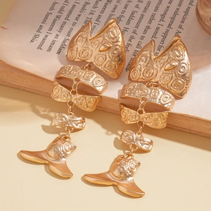 Detailed view of golden fishbone earrings with intricate engravings on a vintage book