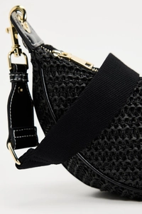 Detailed close-up of black woven shoulder bag with golden zipper and leather accents