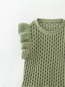 Detail of green knit sleeveless top featuring hollow mesh pattern and ruffle shoulder accents