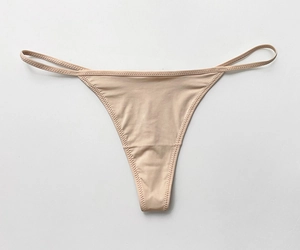Close-up of seamless beige ice silk thong with ultra-thin elastic straps on grey surface