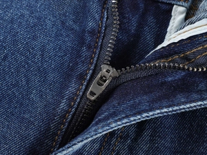 Macro shot of metal zipper and high-quality denim texture on vintage straight jeans
