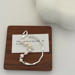 Detail of baroque pearl bracelet with irregular silver twig branch metal frame on wood