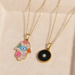 Detailed view of gold Hamsa hand and round Evil Eye charms on bohemian style link chains