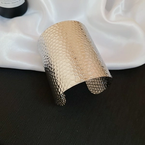 Macro shot of silver textured metal cuff bracelet with hammered honeycomb pattern