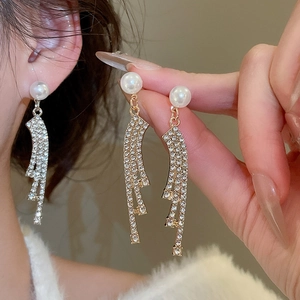 Detail view of long tassel earrings with pearls and rhinestones in silver and gold colors