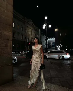 Dettaglio di un elegante abito da sera in raso avorio con spacco laterale e texture lucida