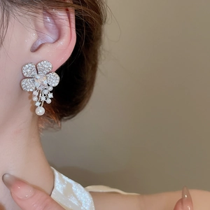Detail of silver flower tassel earrings with zircons and pearls on model