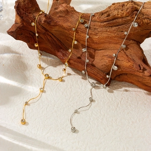 Gold and silver Y-shaped necklaces with heart charms and crystals on a rustic wood block