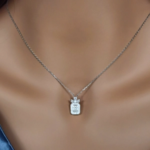 Close-up of S925 silver perfume bottle pendant with bow and stones on a neck chain