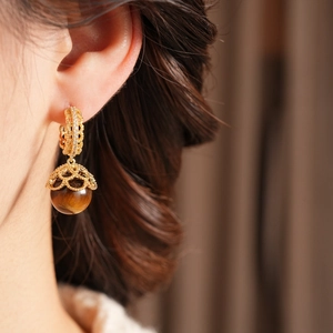 Detailed close-up of vintage gold hollow spherical earrings featuring natural tiger eye stone