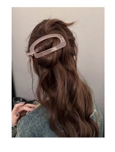 Détail d'une pince à cheveux ovale mate pour cheveux longs bouclés rose poudré chic