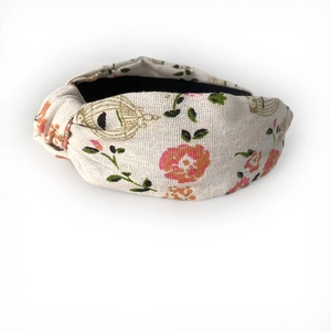 Detail of knot design on beige floral fabric headband with birdcage and leaf pattern