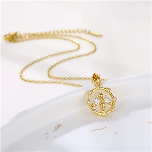 Collier abeille en acier inoxydable doré sur une assiette décorative en céramique blanche