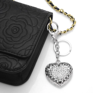 Sparkling silver heart keychain with rhinestones on a black leather camellia handbag