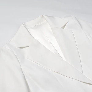 Close-up detail of the deep V-neckline and elegant lapel on this white mini dress