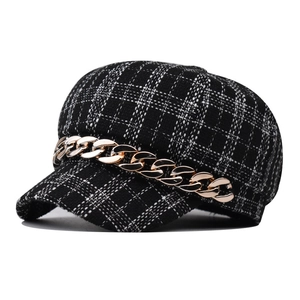 Macro shot of black and white plaid tweed newsboy hat with chunky gold metal chain detail