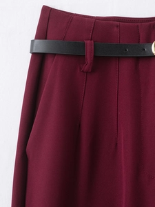 Detail view of burgundy high-waisted trousers with an adjustable black leather belt