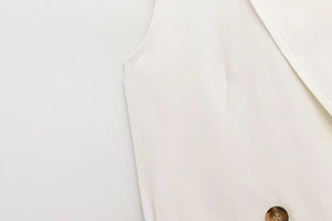 Détail macro du tissu tissé blanc et du bouton à motif ambre marron sur le gilet chic