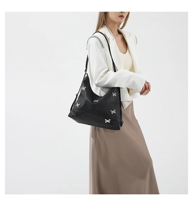 Close-up of black nylon tote bag with decorative silver metal bows and spacious design