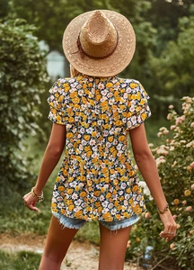 Rear view of floral print top with ruffle sleeves and tiered hem in a garden setting