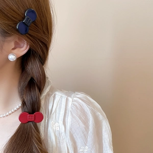 Detailed view of matte resin bow-knot hair clips in red and navy blue on braided hair