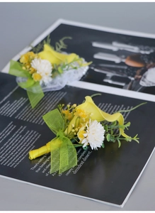 Macro detail of yellow calla lily boutonniere with daisy and green leaf for wedding groom