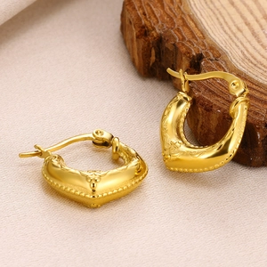 Macro shot of gold geometric hollow earrings with embossed floral texture and bead trim