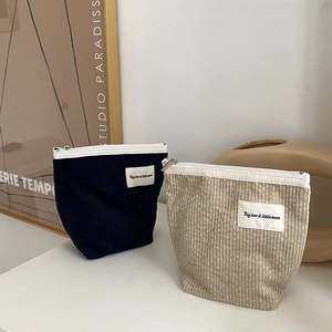 Detail of corduroy makeup bags in navy and beige with premium woven star and moon labels