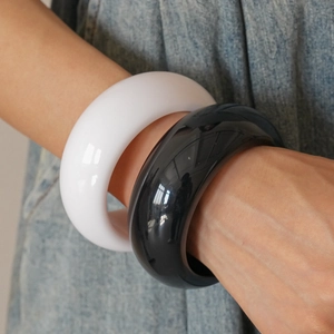 Detail of minimalist black and white resin geometric bangles worn on denim background