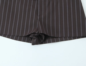 Detail of pinstripe casual shorts showing navy stripes on dark brown fabric and neat stitching