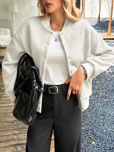 Close-up of white fleece jacket with round neck and snap button closure for autumn wear