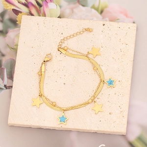 Detalle de una pulsera de doble capa dorada con estrellas y turquesa sobre piedra