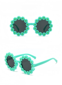 Detail view of flower-shaped children's sunglasses with green daisy frame and grey lenses