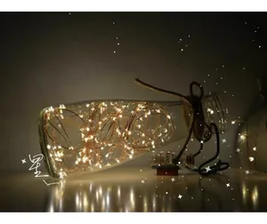 Macro shot of warm LED starry fairy lights inside a clear glass jar with rope detail