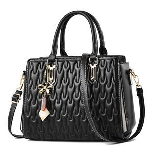 Elegant black quilted handbag with wavy stitching, gold hardware and geometric charm