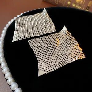 Silver geometric square mesh drop earrings with triangular accents on black velvet background